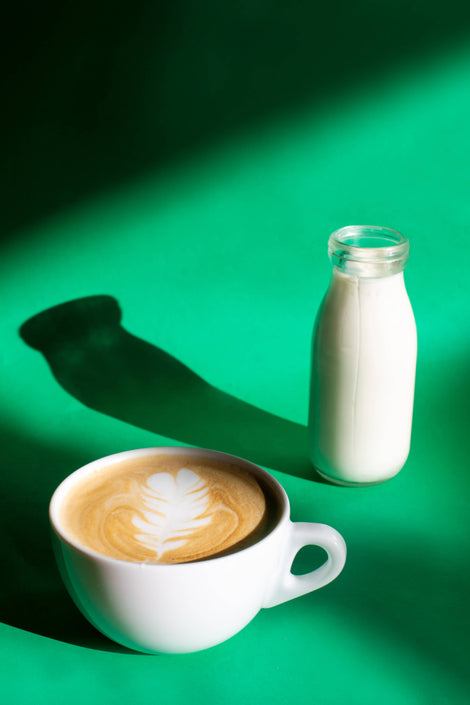 Photo of a latte next to a bottle of milk.